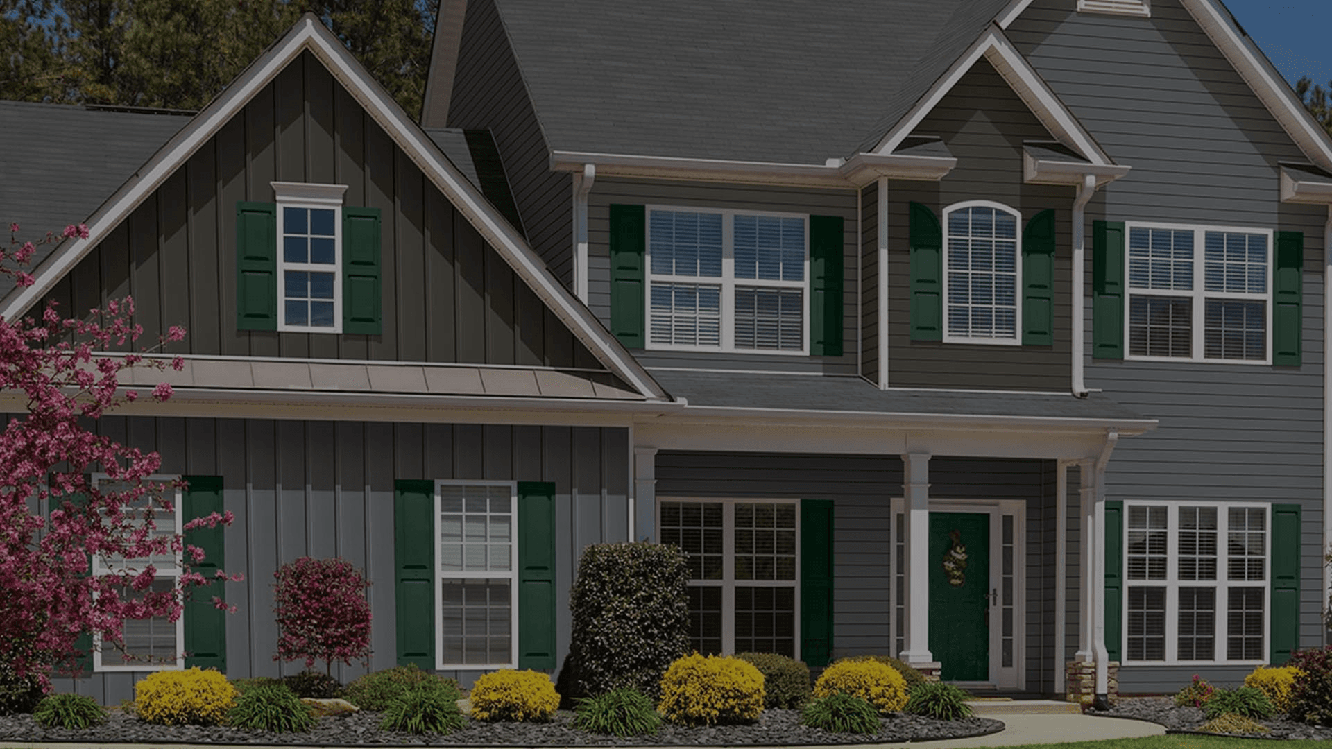 A house with white trim, gray siding, and green shutters.
