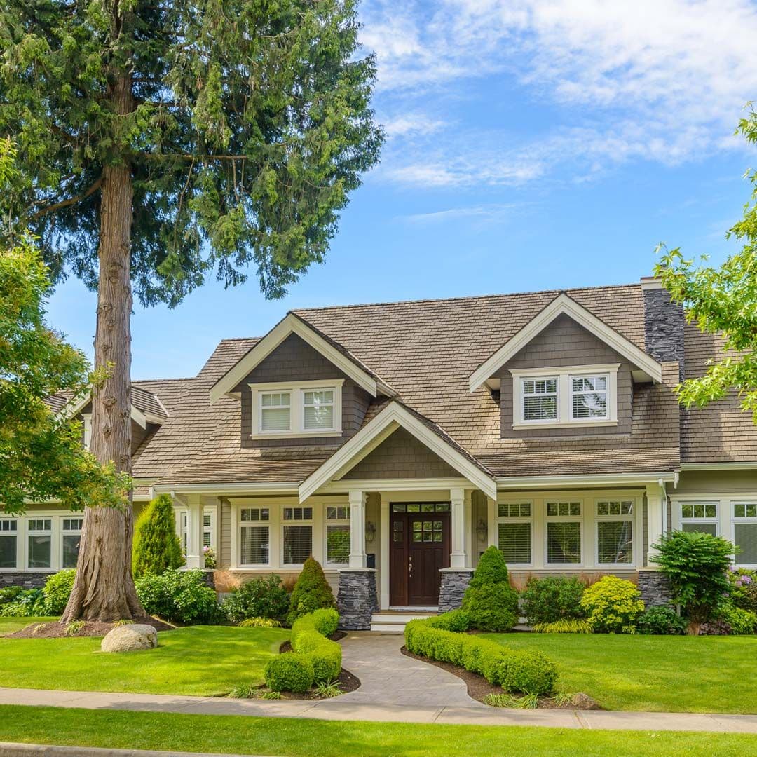 A tan house with new siding, front porch, and brown front door.