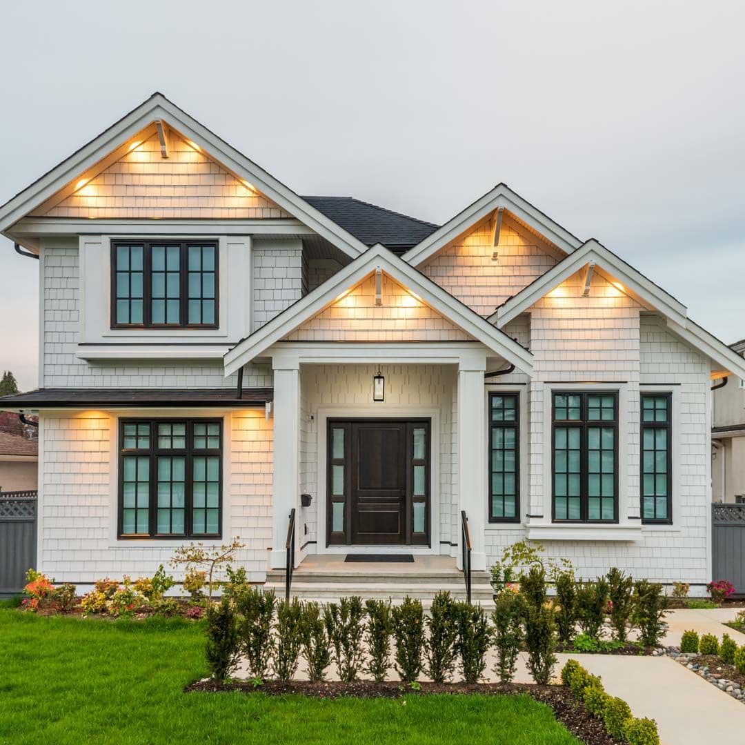 A white house with new shingle siding and windows with black frames.