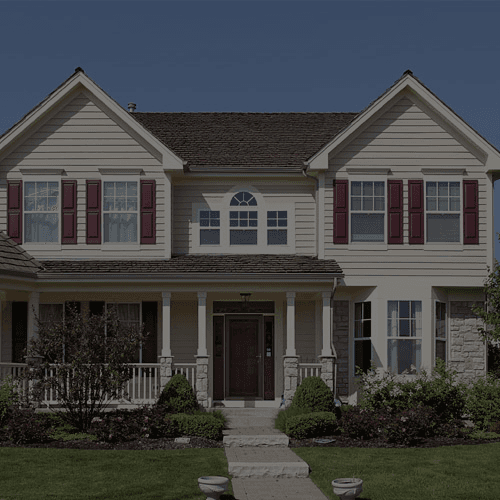 A house with light-colored siding, white trim, and dark red shutters.